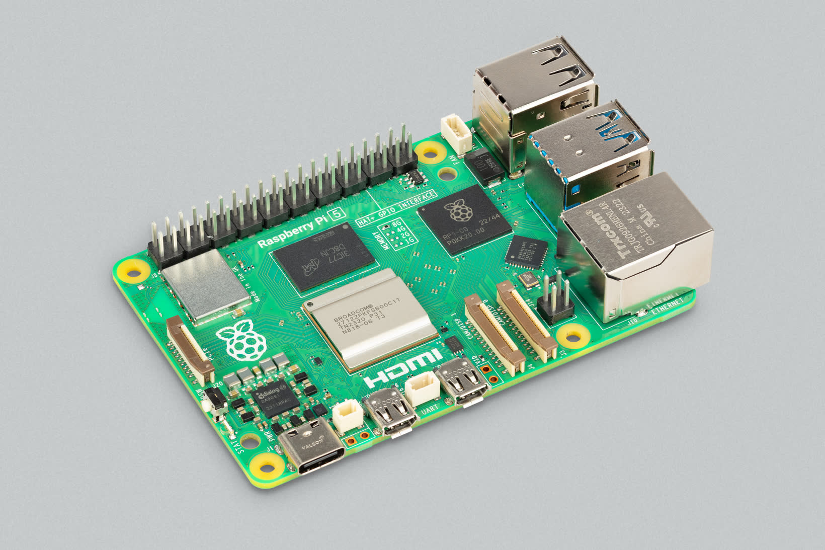 Raspberry Pi 5 single-board computer on a gray surface, angled to show the green board, ports, and GPIO header